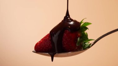 Çilekli kaşık, çikolata damlıyor. Havada kaşık, çileklerin üzerine çikolata dökülüyor. Çikolata kaplı çilekler..