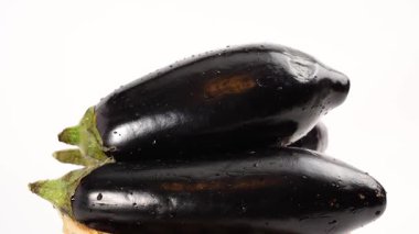 Patlıcanlar birbirlerinin üstüne yatarlar. Patlıcanlar beyaz arkaplanda döner.