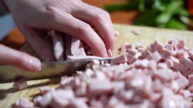 Bir adam kesilmiş bir tahtanın üzerinde pişmiş sosis keser. Sosis küçük parçalara bölünmüş. Bıçak kesmek için kullanılır..