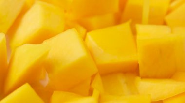 Yavaş çekimde üzerlerine mango suyu dökülen sarı mango dilimleri. Dilimler doğranır ve beyaz arka plana serilir..