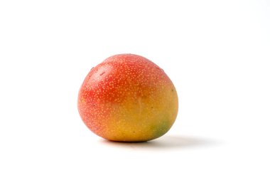 Olgun bir mango beyaz bir arka planda oturuyor. Parlak kırmızı ve sarı renkli küçük yuvarlak bir meyvedir.