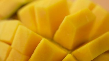Derisi yüzülmüş sarı bir mango. Mango küçük parçalara bölünmüş.