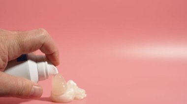 Pembe arka planda bir şişe tıraş jeliyle. Tıraş jölesi pembe arka planda şişeden sıkılarak çıkarılır..