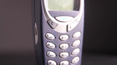 Eski tuşlu cep telefonu koyu bir arkaplanda dönüyor. Tuşlu cep telefonunu kapat.