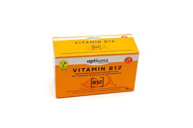 Almanya 28 Mart 2025. Bir kutu B-12 vitamini. Turuncu ve beyaz. Optisana şirketinden. B12 koyu bir arkaplanda izole edildi.