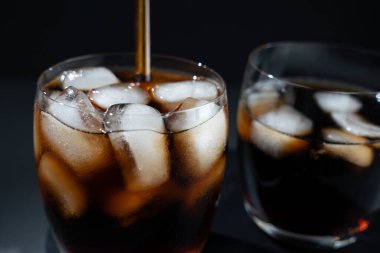 İçinde buz küpleri olan bir bardak soda. Bardakta bir pipet var.