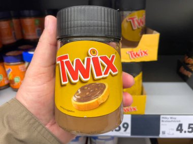Almanya 29 Mart 2025. Bir kavanoz Twix bir kişi tarafından tutuluyor. Kavanoz sarı ve siyah kapağı var.