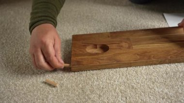 Bir insan mobilya montajı yaparken tahtaya tahta iğneler yerleştiriyor. Bir kişi mobilya montajı yapar.