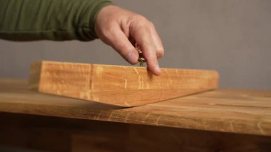 Elektirikli tornavida kullanan bir adam vidaya vida sokuyor. Bir adam mobilya montajı yapıyor..