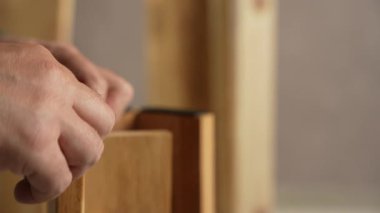 Adamın biri bir parça yumuşak bandı bir mobilyanın tahta bacaklarına yapıştırıyor. Bir adam mobilya montajı yapıyor..