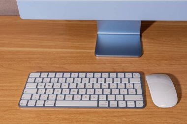 Almanya 7 Nisan 2025. Bir bilgisayar klavyesi ve fare ahşap bir masanın üzerinde. Klavye beyaz ve sol üst Apple bilgisayarında siyah bir tuş var..