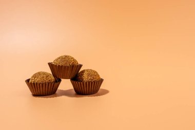 Üç kahverengi kek üst üste istiflenmiş. Kekler kahverengi kağıt bardaklarda.