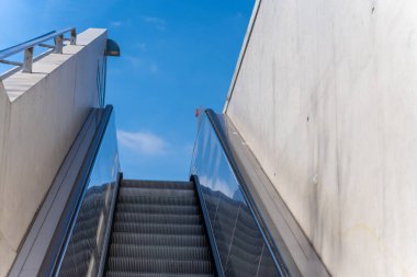 Metrodan çıkan yürüyen merdiven yukarı çıkıyor. Mavi gökyüzüne karşı yürüyen merdiven.