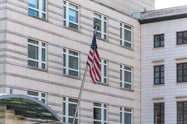 Üzerinde bayrak direği ve Amerikan bayrağı olan yüksek bir bina. Bina beyaz ve birçok penceresi var. Bayrak yüksekte dalgalanır ve yerden kolayca görülebilir.