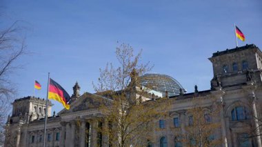 Üzerinde kubbe ve bayraklar dalgalanan Reichstag binası. Almanya Bayrakları.