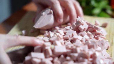 Bir adam kesilmiş bir tahtanın üzerinde pişmiş sosis keser. Sosis küçük parçalara bölünmüş. Bıçak kesmek için kullanılır..