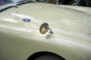 Krom yan aynalı krem renkli klasik araba. Çamurluğa monte edilmiş yuvarlak krom yan aynalı krem beyazlı klasik bir araba çevreyi yansıtıyor. Pürüzsüz kıvrımlar ve cilalanmış bitiş klasik otomobilin zarafetini vurguluyor