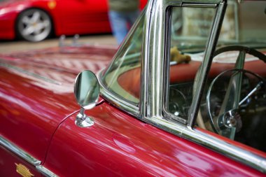 Üstü açık kırmızı klasik bir arabanın krom yan aynası. Ayna ön çamurluğa monte edilmiş. Aerodinamik retro tasarımı sergiliyor..