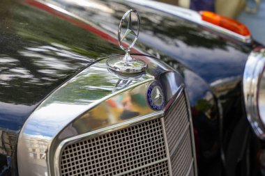 Almanya 11 Mayıs 2025. Mercedes klasik araba yıldızı amblemi. Klasik Mercedes-Benz kaput süsü ve klasik bir model üzerinde ızgara detayı. Üç köşeli yıldız parlak siyah bir yüzey üzerinde duruyor..