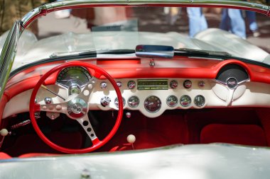Almanya 11 Mayıs 2025. Beyaz ve kırmızı Corvette paneli. Klasik bir Corvette 'in kokpitine muhteşem bir bakış: Kırmızı direksiyon, krom ayrıntılar ve eğri aletler 1950' lerin tasarımını yansıtır..