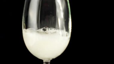 Köpüklü beyaz şarap dökülüyor. Beyaz köpüklü şarap ya da şampanya dökülürken ince bir köpük tabakası bir bardakta oluşur. Parlak bir anın zarif bir tasviri..