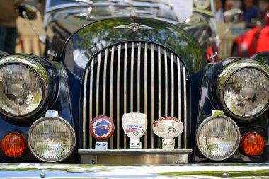 Almanya 11 Mayıs 2025. Morgan 4 / 4 Rozetli. Sayısız tarihi miting rozeti olan bir Morgan 4 / 4 'ün önünde. Klasik farlarla çevrili dikey ızgara İngiliz çekiciliğini ödünç verir..