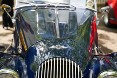 Almanya 11 Mayıs 2025. Morgan 4 / 4 kaput ve amblem. Mavi bir Morgan 4 / 4 'ün kıvrımlı kaputu gün ışığını yansıtır. Klasik amblem ve hava menfezleri İngiliz roadster tasarımını vurguluyor.