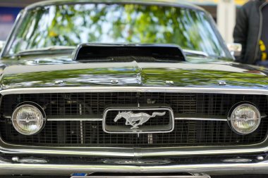 Almanya 11 Mayıs 2025. Ford Mustang Ön Görünümü. Efsanevi Ford Mustang dörtnala koşan atıyla ızgarada zengin siyahlar içinde parlıyor. Ön görüş Amerikan araba kültürünün bir ifadesidir..