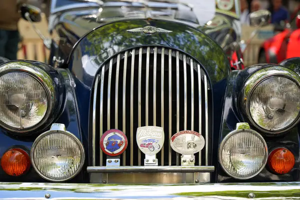Almanya 11 Mayıs 2025. Morgan 4 / 4 Rozetli. Sayısız tarihi miting rozeti olan bir Morgan 4 / 4 'ün önünde. Klasik farlarla çevrili dikey ızgara İngiliz çekiciliğini ödünç verir..