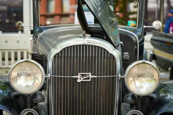 Almanya 11 Mayıs 2025. Buick Vintage Car Front. Radyatör kapağı açık tarihi bir Buick 'in önünde klasik farlar ve süslü bir ızgara görülüyor. Parlak logo ve çizgiler nostaljik bir cazibe taşıyor..
