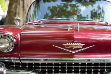 Almanya 11 Mayıs 2025. Cadillac 'ın önü. Çarpıcı bir amblemi ve detaylı bir ön ucu olan kırmızı bir Cadillac klasik araba. Parlak krom detaylar 1950 'lerin cazibesini yansıtıyor..