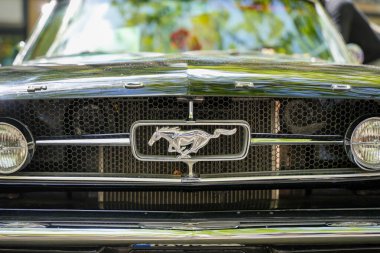 Almanya 11 Mayıs 2025. Ford Mustang ön ızgarası. Ford Mustang 'in ızgarasında dörtnala koşan ikonik Mustang. Krom detaylara sahip bal peteği ızgarası gücü ve Amerikan otomotiv geleneğini temsil ediyor..