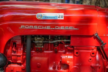 Almanya 11 Mayıs 2025. Porsche Diesel Traktör. Yakın plan. Görünür kablolar ve metal parçalarla kırmızı bir Porsche Diesel Traktör 'ün detaylı görüntüsü. Parlak yüzey dikkatli bir restorasyona işaret ediyor..