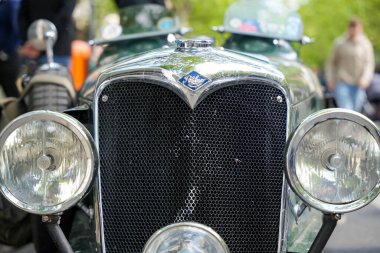 Almanya 11 Mayıs 2025. Riley ızgara ve farlar. Krom ızgaralı ve yuvarlak farlı klasik bir Riley arabasının ön görüntüsü. İnce detaylar savaş öncesi İngiliz araçlarının tarzını yansıtıyor..