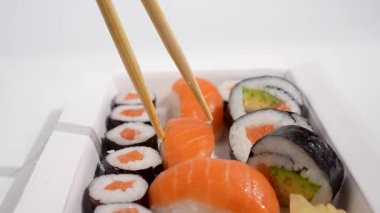 Ön planda yemek çubukları olan suşi. İki çubuk, suşi kutusundan somon nigiri alır. Odaklanma anı kapma anıdır..