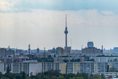 Berlin TV Kulesi odak noktasında, apartman blokları ve şehrin simgeleriyle çevrili. Ufuktaki sis sermayenin enginliğini ve yoğunluğunu vurguluyor..
