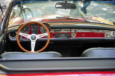 Almanya 11 Mayıs 2025. Klasik üstü açık bir arabanın içi. Tahta direksiyonu ve kırmızı enstrümanları var. Ahşap ve krom kombinasyonu 1960 'ların zarif tarzının altını çizer.