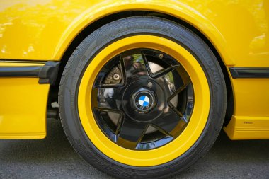 Almanya 11 Mayıs 2025. Siyah yıldız desenli ve Dunlop lastikli sarı boyalı bir BMW. Boya çalışmasındaki yansıma çevreyi vurguluyor ve görüntüyü özellikle canlı kılıyor..