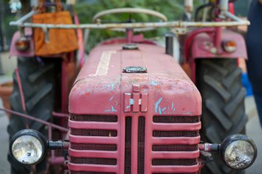 Farmall Traktör Cephesi. Önünde yuvarlak farlar ve yıpranmış boya bulunan traktör yıllar öncesinden bahsediyor. Aşınma belirtileri gerçekçilik katar.