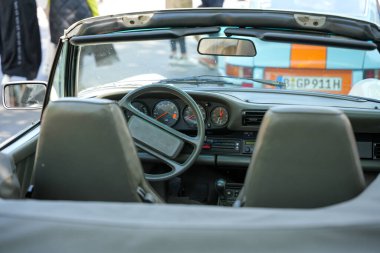 Porsche Cabriolet iç mekan. Açık bir Porsche Cabriolet 'in içinde spor bir direksiyon ve yuvarlak enstrümanlar bulunur. Sahne açık, dinamik ve gitmeye hazır görünüyor..