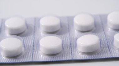 Haplara yakın çekim. Su toplayan bir paketin içindeki hapları yakın plan çek. Beyaz arka planda dönen su toplayan beyaz haplar.