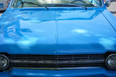 Almanya 11 Mayıs 2025. Oldsmobile cephesi, mavi. Koyu mavi boyalı bir Oldsmobile 'in ayırt edici ızgarası, parlak finaliyle çevresini yansıtır. Merkezdeki klasik amblem görüntüye nostaljik bir karakter katıyor..