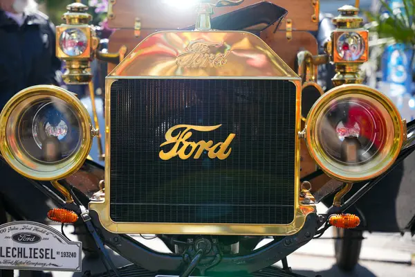 Almanya 11 Mayıs 2025. Ford Model T logolu ön manzara. Siyah ızgarasında altın rengi harfler olan Ford Model T 'nin ön görüntüsü. Parlak farlar canlı ticaret gösterisi atmosferini yansıtıyor..