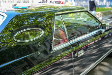 Almanya 11 Mayıs 2025. Lincoln Mark 5, amblemli yan görüş. Lincoln Mark V 'in şık bir opera penceresi ve krom çerçeveli Lincoln logosu olan detaylı görüntüsü. Parlak siyah onun çevresini zarifçe yansıtır..