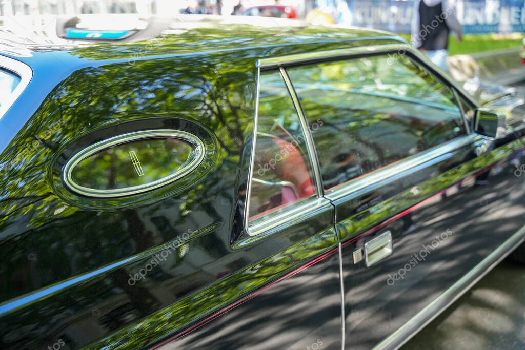 Germany Berlin May 11, 2025. Lincoln Mark V, side view with emblem. Detailed view of a Lincoln Mark V with a stylish opera window and the Lincoln logo in a chrome frame. The glossy black elegantly reflects its surroundings.