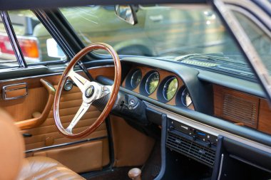 Almanya 11 Mayıs 2025. İçi ahşap direksiyonlu, yakın plan. Tahta direksiyon, analog kadranlar ve kahverengi deri döşemeler bu klasik aracın lüks karakterini gösteriyor. Detaylara dikkat etmek t 'nin tasarımını tanımlar