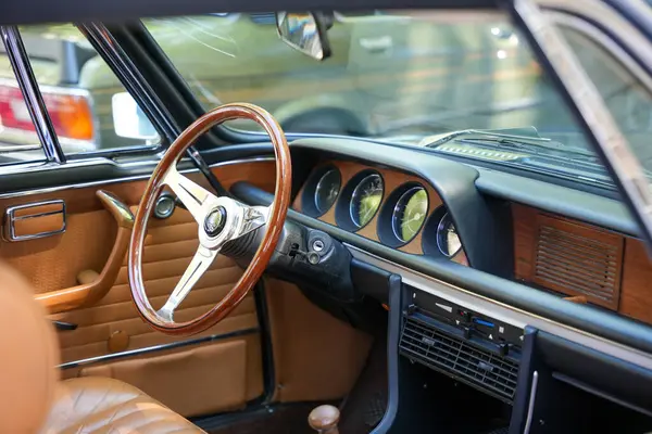 Almanya 11 Mayıs 2025. İçi ahşap direksiyonlu, yakın plan. Tahta direksiyon, analog kadranlar ve kahverengi deri döşemeler bu klasik aracın lüks karakterini gösteriyor. Detaylara dikkat etmek t 'nin tasarımını tanımlar