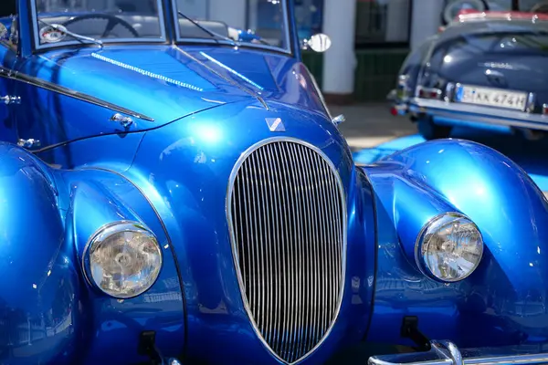 Almanya 11 Mayıs 2025. Kendine özgü ızgarası olan mavi klasik bir araba. Kıvrımlı çamurlukları ve dikey ızgarası olan şık mavi klasik bir araba. Gün ışığında gerçek bir göz alıcı. Vücut zarifçe çevresini yansıtır..
