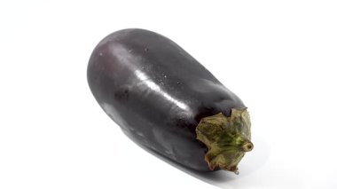 Patlıcanın yan görünüşü. Patlıcan beyazda döner. Taze patlıcan beyaz arka planda yatay olarak uzanır..