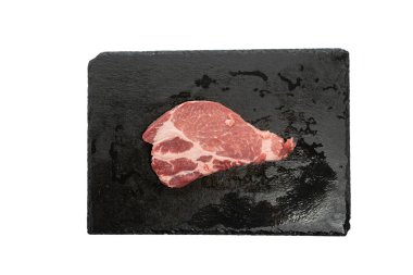 Slate Slab 'de Tek Biftek Üst Manzarası. Siyah bir levhada çiğ domuz bifteği. Sunum, yemek tarifi ya da talimatlar için mükemmel. Beyaz arkaplanda izole edilmiş et.